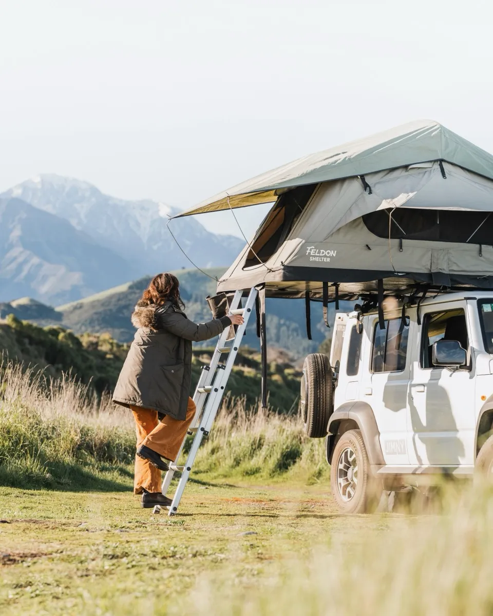 A rooftop tent set up on a Jimny in the high country at golden hour.