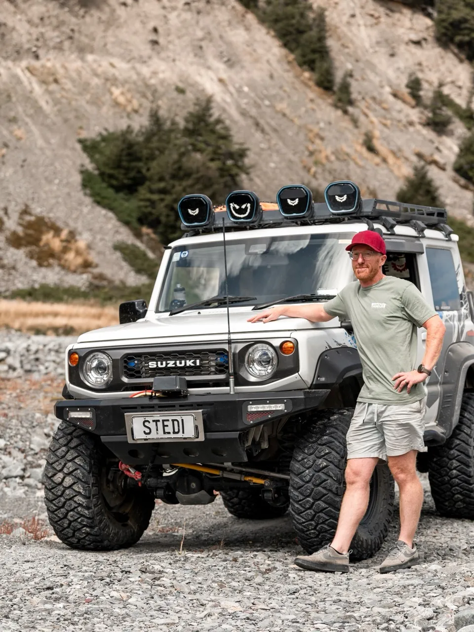 Adam Crouchley beside his kitted-out Suzuki Jimny in a South Island river valley.